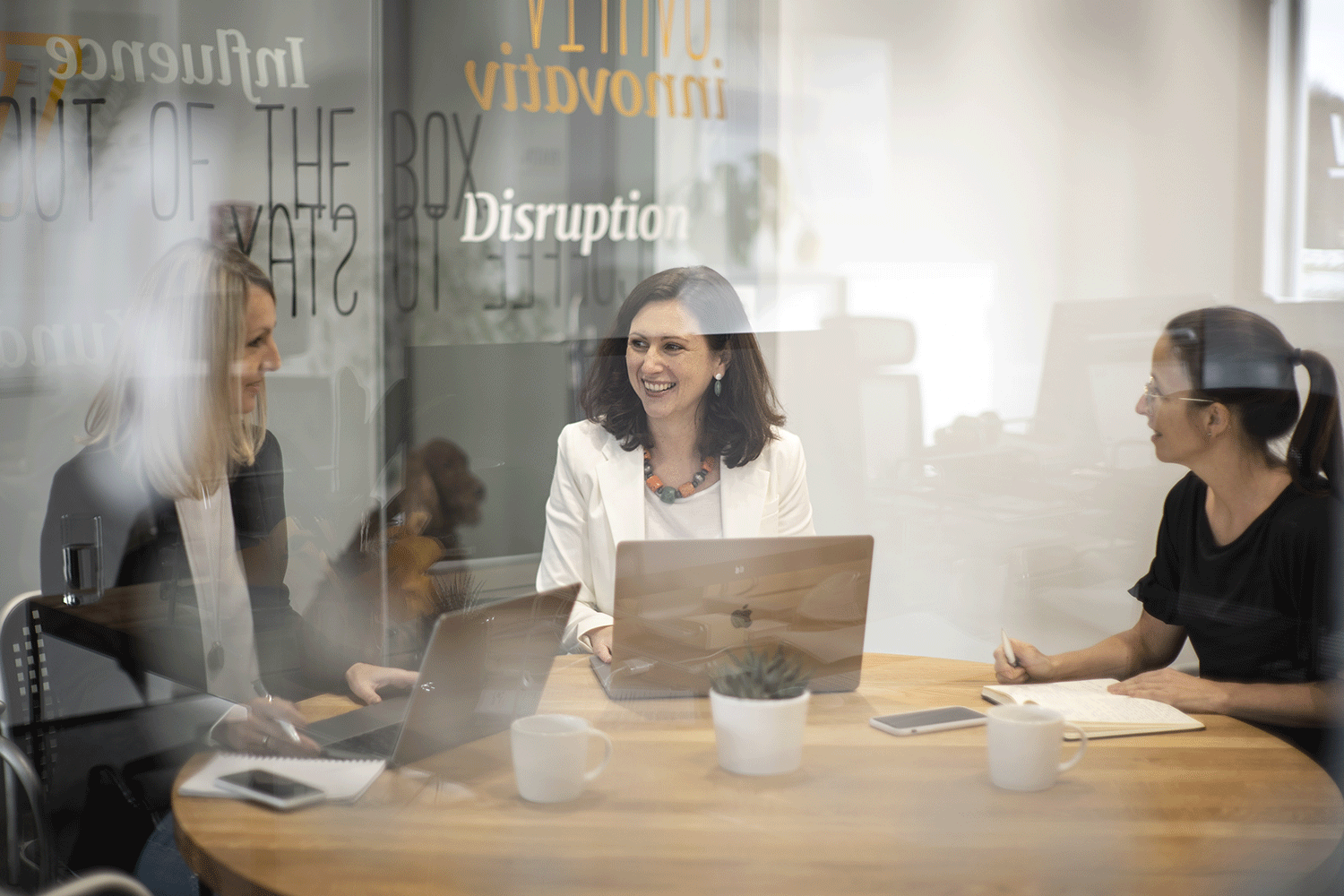 Hotline drei fröhliche business frauen in besprechung mit laptop und notizblock